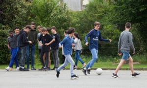 Children play football and chat in the playground.