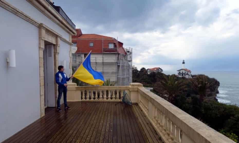 One of the activists on an upper-floor balcony of the Alta Mira villa in Biarritz with a Ukrainian flag.