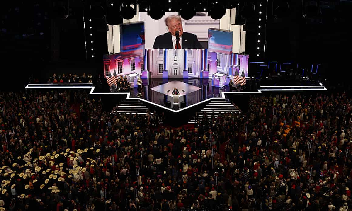 A wide crowdshot of the Republican national convention in Milwaukee, Wisconsin, watching Donald Trump speak, his face projected on a large screen in the front