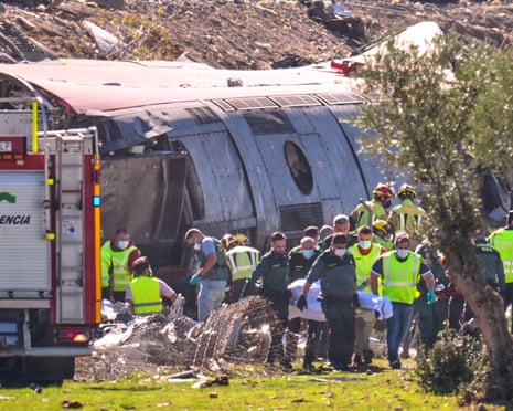 Emergency responders carry a stretcher past a derailed train carriage after a collision in Spain