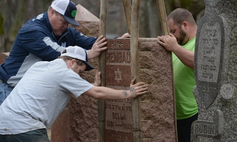 Volunteers from a local monument company help to reset vandalized headstones at Chesed Shel Emeth Cemetery.