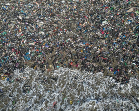 O mar chega a uma praia completamente coberta de tecidos descartados