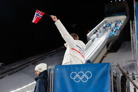 A Norway coach uses a flag to signal when it’s good to jump at the men’s ski jump.