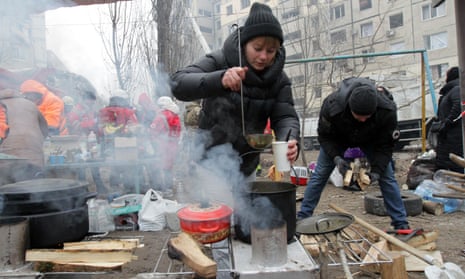 A woman ladles out soup outside the apartment block hit by a rocket launched by Russian occupiers during a missile attack on Ukraine, as search and rescue operations and work dismantling dangerous structures continue.