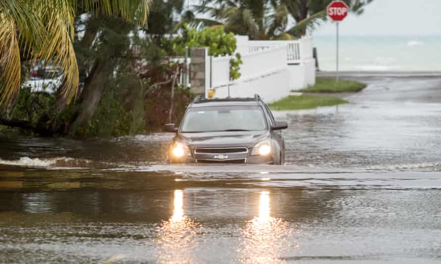 A car drives through a flooded street in Nassau.