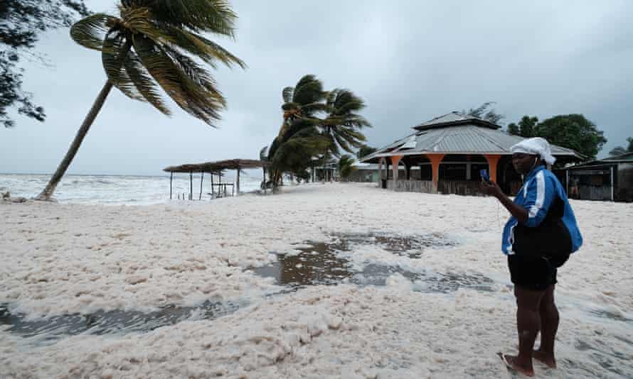 Hurricane winds across a beach being filmed by a woman