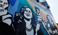 A bold mural with black-and-white images of people, including Kamala Harris, among rays of color.