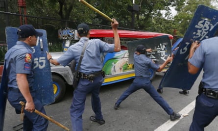 Police officers hit fleeing protesters outside the US embassy in Manila