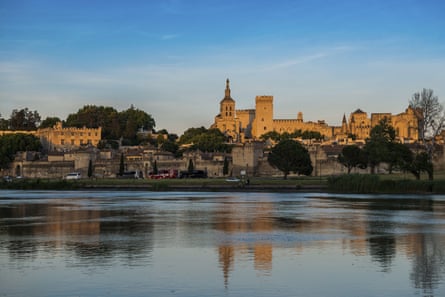 A river with a golden-stoned palace complex on the bank behind it
