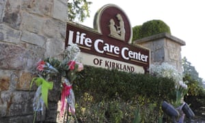 Flowers left next to the sign that marks the entrance to the parking lot of the Life Care Center in Kirkland.