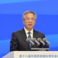 Hu speaks behind a podium against blue background