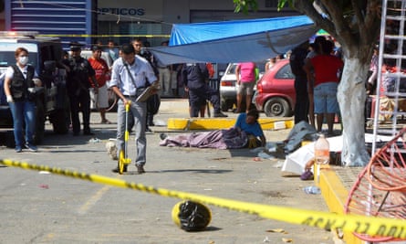 A woman cries over the corpse of her murdered family member while forensic personnel work at the scene of the crime in the parking lot of a shopping center in Acapulco, Guerrero, Mexico, on 4 January 2017.