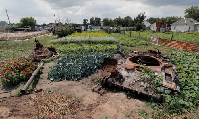Vegetables grow next to the destroyed hulk of a Russian military vehicle at a garden in the village of Velyka Dymerka, Ukraine