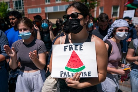 a person holds a sign that reads "free Palestine" with a drawing of a watermelon slice