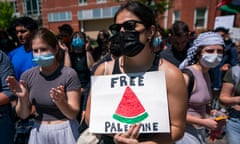 a person holds a sign that reads "free Palestine" with a drawing of a watermelon slice