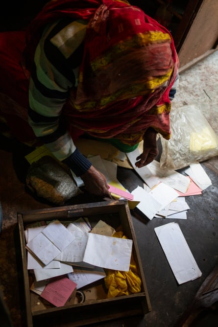 Nur Jahan from above, looking through papers in a wooden box on the floor.