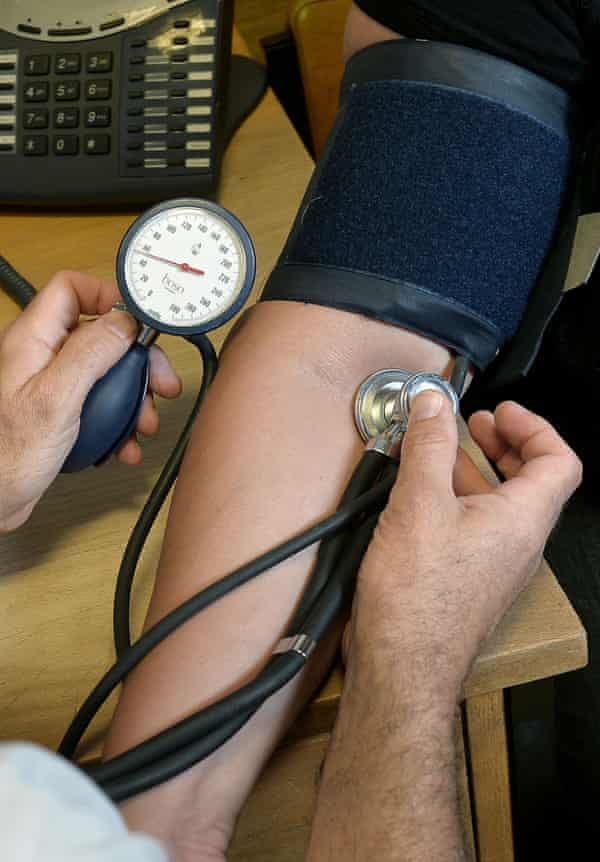 um médico mede a tensão arterial com uma manga à volta do braço e um estetoscópio