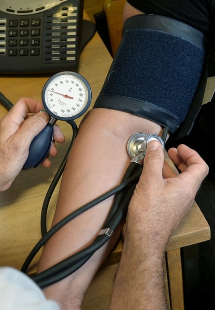 a doctor takes someones blood pressure with a sleeve around their arm and a stethoscope