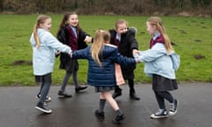 A group of children play ring a roses outdoors during their school break
