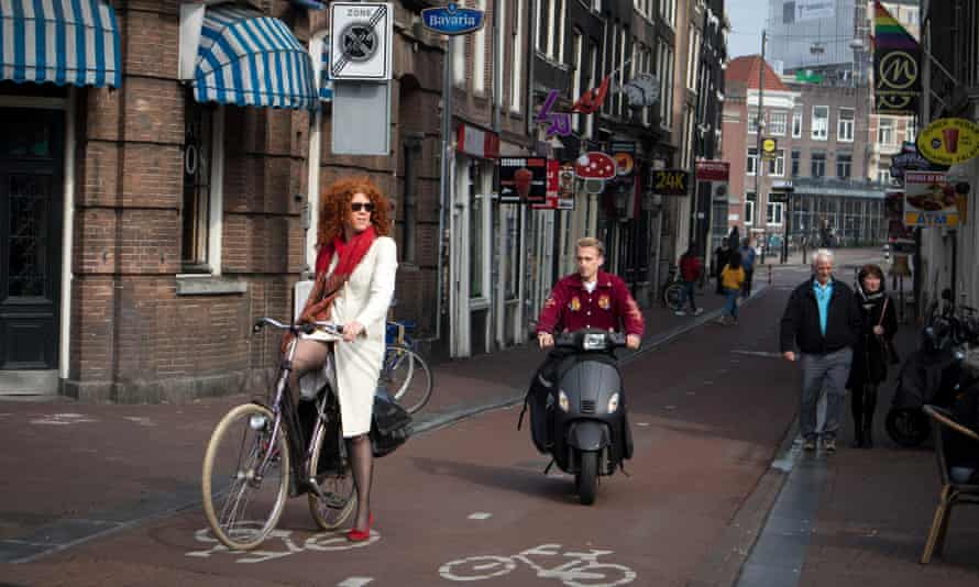 A cyclist and a moped rider share a bike lane.