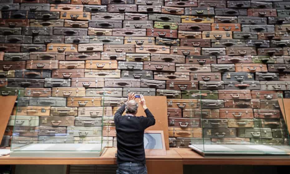 A visitor at the opening of the main exhibition of the Museum of the Second World War in Gdańsk, Poland. He is taking a picture in front of a display of piled up suitcases representing deportation.