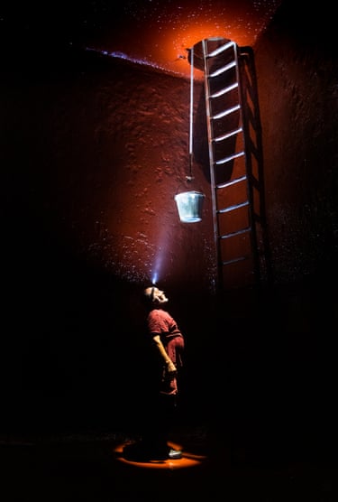 A man stands wearing a head torch in an underground wine tank