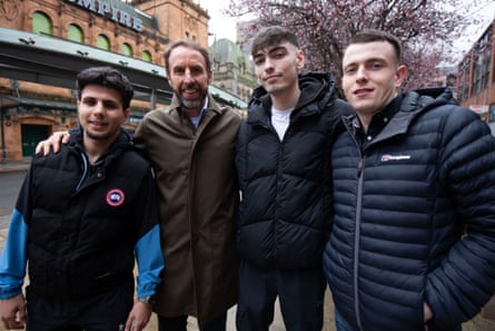 Gareth Southgate stands in the street with his arm around three young men