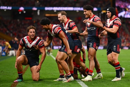 Mark Nawaqanitawase kneels after scoring a try as his teammates beging to celebrate with him