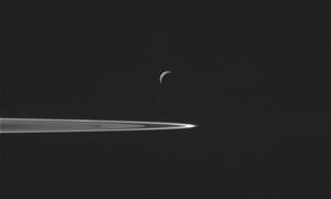 This image shows Saturn’s moon Enceladus, center, as the Cassini spacecraft prepared to make a close flyby of the icy moon. A portion of the planet’s ring is at right.