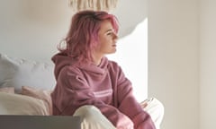 Thoughtful pensive teen hipster girl pink hair wear hoodie sit in bed with laptop take break from studies think of inspiration look away, reflect, dreaming, feel melancholic lost in thoughts. Vertical