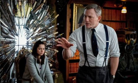 Actor Ana De Armas sits on a chair surrounded by knives as Daniel Craig gestures in a still from Knives Out