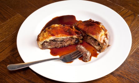 Steak and kidney pie cut open and with a fork on a round white plate