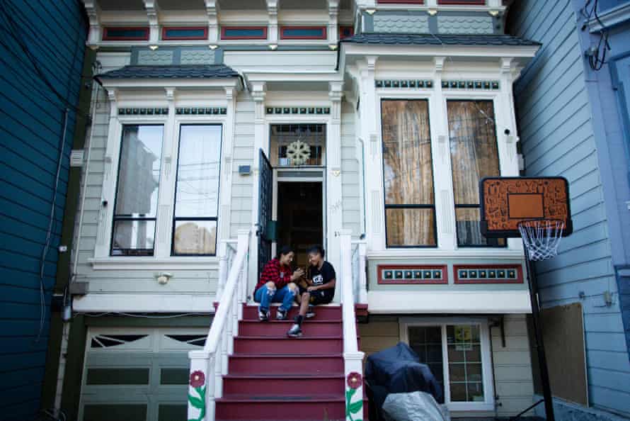 Cousins ​​Maggie Guillen, 12, left, and Noe Zuleta, 14, sit on the front steps of their home in the Mission District.