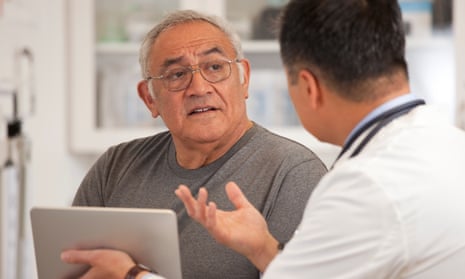 A doctor using a digital tablet to talk to a male patient.