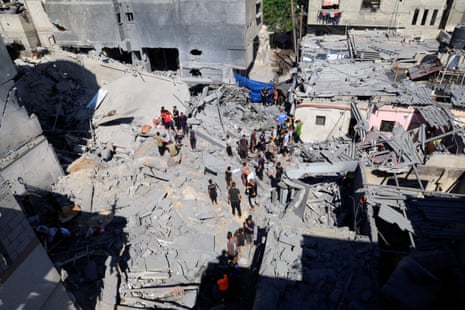 Palestinians inspect the site of an Israeli strike on a house in Deir Al-Balah.