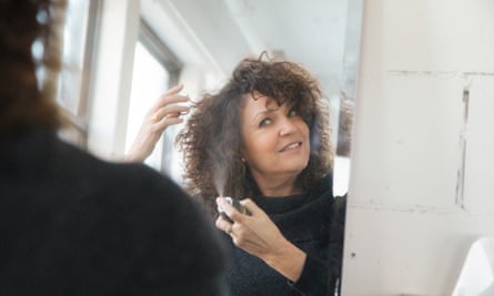 Woman applying dry shampoo to her hair at home.
