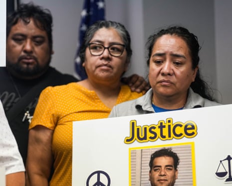 A woman looking sad and looking down holds a sign with a man's photo and the word "Justice" above it.