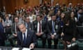 Antony Blinken addresses the Senate’s foreign relations committee: he is sitting at a desk with a microphone in the Senate, with senators seen behind him, and at the back of the room, a group of protesters who are holding up their red-painted hands.