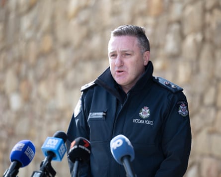 Policeman in uniform speaking into an array of media microphones
