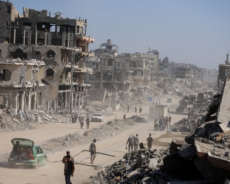Palestinians walk past the rubble of destroyed buildings, amid a ceasefire between Israel and Hamas, in Gaza City.