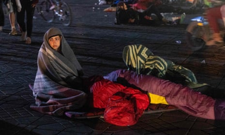 A young woman wrapped in a blanket on a street.