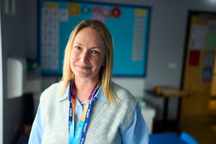 Patricia Maxwell stands smiling in a classroom, colourful display board behind her