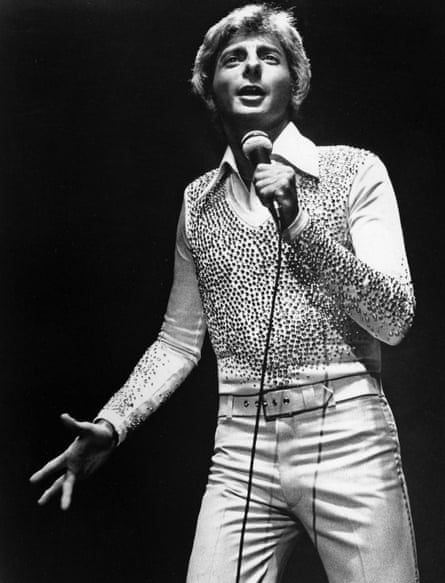 Black and white photo of Barry Manilow holding a microphone on stage
