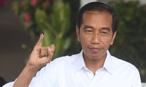 Joko Widodo shows his ink-stained finger after casting his vote in Jakarta