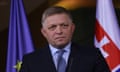 Robert Fico dressed in suit in front of flags