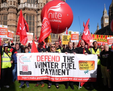 People hold banners and flags at a protest in London against the cuts to winter fuel payments
