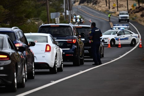 A Maui police officer blocks a road to prevent residents and visitors from driving to Lahaina.