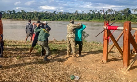 Environmental agents frisk suspected miners at a blockade along the Uraricoera river