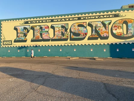 A pedestrian walks by a mural depicting the history, culture and economy of Fresno.