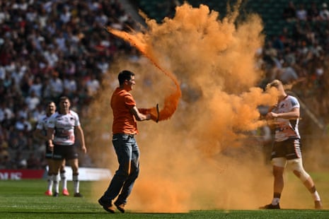 An activist from the environmentalist group "Just Stop Oil" spreads orange powder after entering the pitch as a sign of protest during the Premiership Final rugby union match between Saracens and Sale Sharks at Twickenham Stadium.